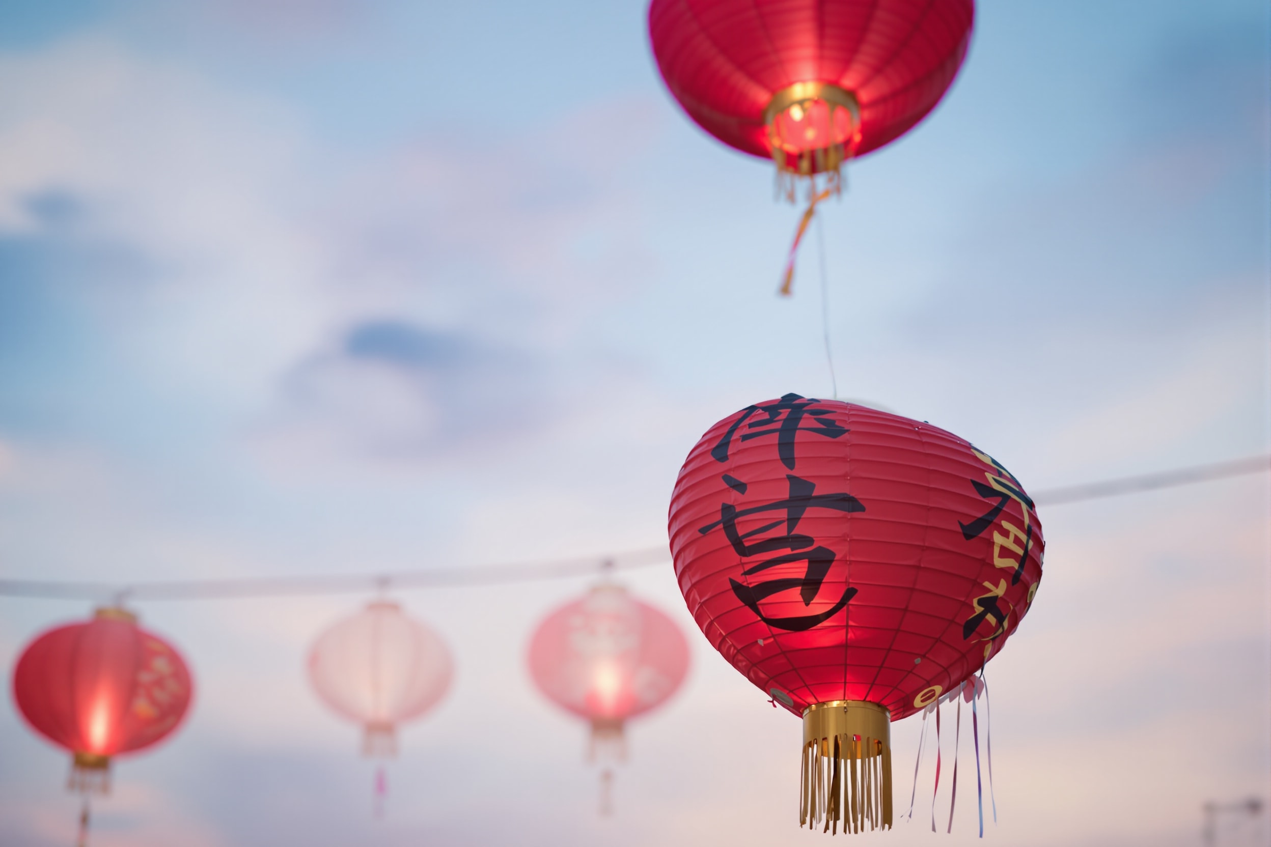 Colourful festival balloons and red paper lanterns against a dusk sky
